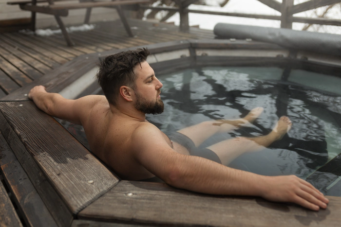 Un homme profitant d'un jacuzzi et spa en plein air à la montagne